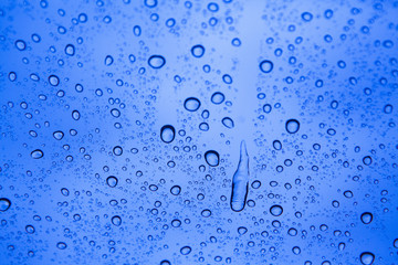 Water drops on glass with blue background