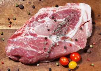 Pork steak on the wooden background with pepper, thyme and cherry tomatoes