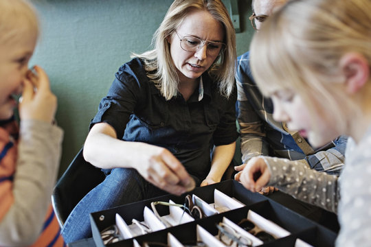 Family arranging eyeglasses in box at workshop