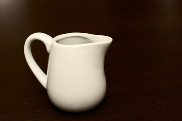 White milk jug on the wooden background