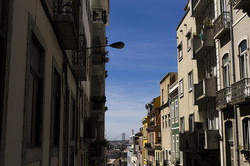 Fototapeta na wymiar Streets of Lisbon, beautiful view with architecture and bridge on backgrounds. Portugal. Blue sky. Sunny weather.Typical tiles in buildings. Holidays and travelling.