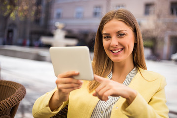 Beautiful young woman using digital tablet while sitting at the cafe.