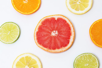 Fototapeta na wymiar cut citrus slices orange, grapefruit, lemon, lime, tangerine on a white background filled with water 