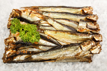 smoked sprats and parsley on white paper