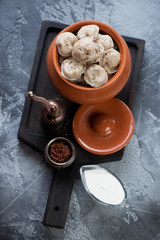 Ceramic pot with boiled russian meat dumplings pelmeni over grey stone background, high angle view