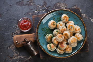 Turquoise plate with fried meat dumplings or pelmeni, top view on a dark brown stone background