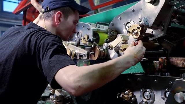 Employee of the printing press adjusts his equipment