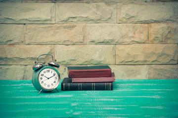 vintage alarm clock with old book on wood