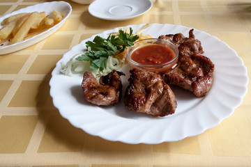 pork shish kebab with tomato sauce on a white plate