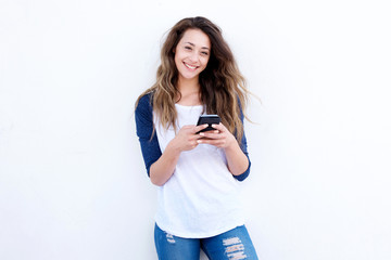 cool young woman smiling with mobil phone against white background