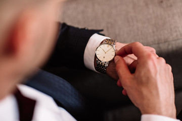 watch with white dial on the hand of a man in a white shirt - 151256471