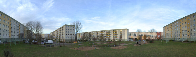 Fototapeta na wymiar Backyard of Plattenbau complex with playground and parking lot in Greifswald, Germany