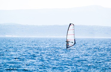 Windsurfer surfing on blue sea