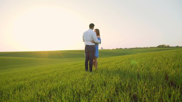 Couple in love stands in embraces, looking and kissing each other on the horizon