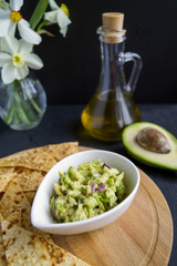 Green homemade Guacamole with chips. black background
