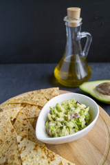Green homemade Guacamole with chips. black background