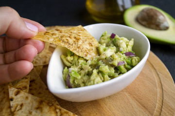 Green homemade Guacamole with chips. black background