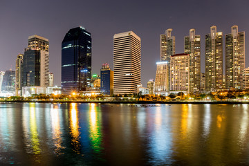 Fototapeta na wymiar Benjakitti public park in Bangkok city in the twilight with skyscrapers and lights reflecting in the lake.