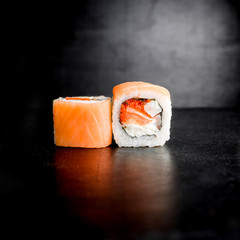 Sushi rolls with fish on black background. Japanese traditional food.