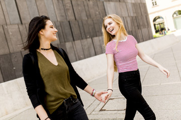 Two young women holding up the hand and walk around. Urban concept