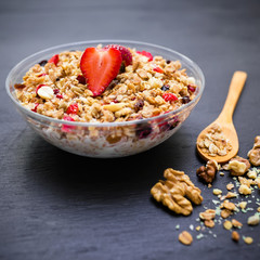 Oatmeal porridge with blueberries, strawberries, muesli and a spoon on wooden background. Top view. Diet breakfast.