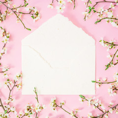 Floral round frame of white flowers and envelope on pink background. Flat lay, top view. Spring time background.