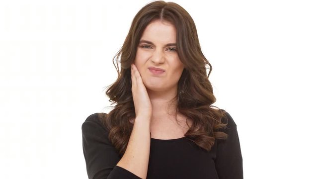 Unhappy Caucasian brunette female in black dress standing on white background and shaking head in disbelief