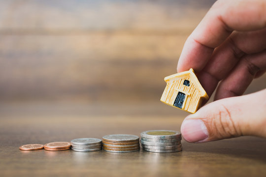 Coin money and house model on wooden background