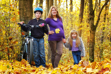 Pregnant mother walking in the park with her son and daughter