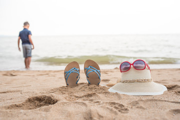 Sandals were buried in the sand. Near the hat and sunglasses