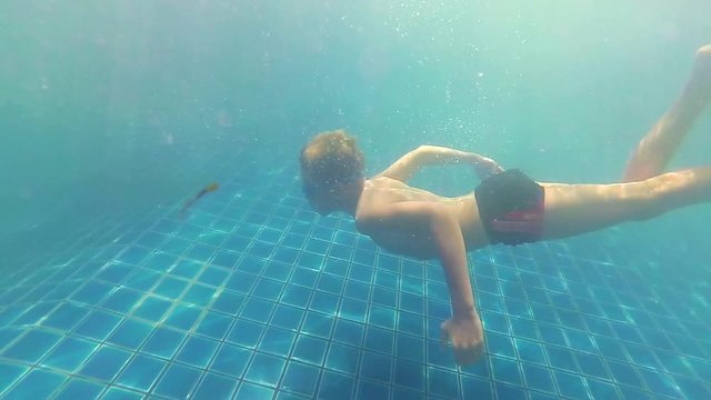 happy child swims with enjoyment under the water in the pool