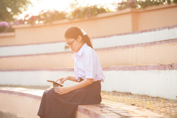 Thai student girl teenager using tablet at the park