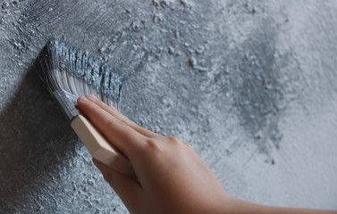 Hand holding brush painting white color to the concrete wall