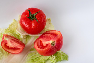 Tomato and tomato slices on a salad leaf on the white background