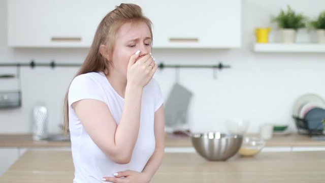 Pretty woman coughing in the kitchen