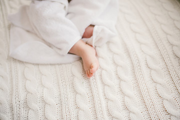 beautiful smiling newborn baby boy covered with white bamboo towel with fun ears. Sitting on a white knit, wool plaid bright interior. The ight from the window