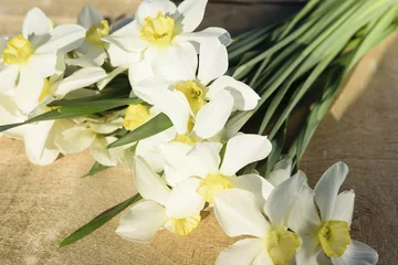 Foto op Canvas A bouquet of daffodils lies on a wooden background © Oleg Picolli