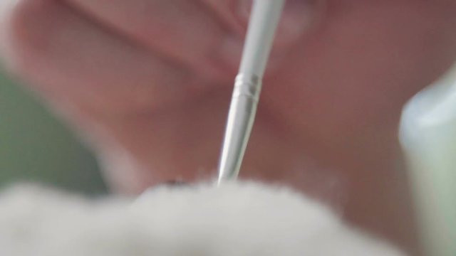Creating a teddy bear: the master draws a nose toy. Teddy bear: the process of creation. The master draws a nose for a teddy bear in an old-fashioned style. A rare collectible toy is a teddy bear.