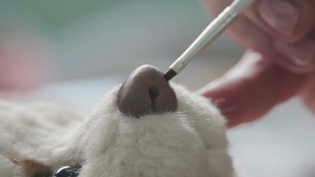 The process of creating a teddy bear: the master draws a nose toy. Fine brush for drawing: the nose of a soft toy. Teddy bear in vintage style: the process of creation. Details of teddy bear
