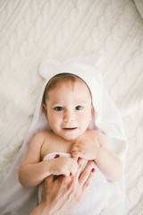 beautiful smiling newborn baby boy covered with white bamboo towel with fun ears. lies on a white...
