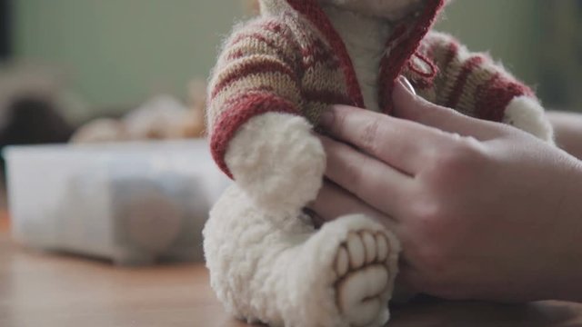 A teddy bear in a red Scandinavian sweater. Collectible soft toy - a teddy bear, as in the 20th century. A toy in vintage style is made by hand. Cute white teddy bear on a separate background.