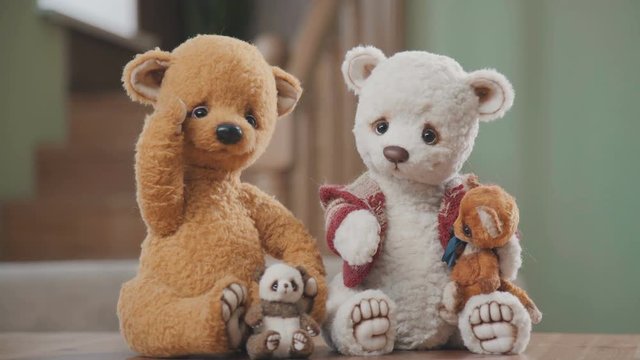Plush bears handmade: two large teddy bears and two small ones on the table. Collectible soft toy - a teddy bear, as in the 20th century. A toy in vintage style is handmade. Old-fashioned teddy bears