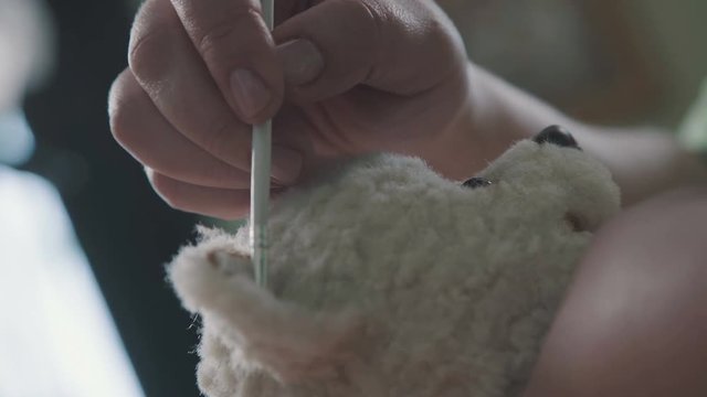 The process of creating a teddy bear: the master paints the ears with a toy. Thin brush for drawing: the ears of a soft toy. Teddy bear in vintage style. Brush is drawn with the details of the toy.