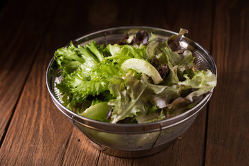 Crisphead lettuce in a bowl on wooden table.