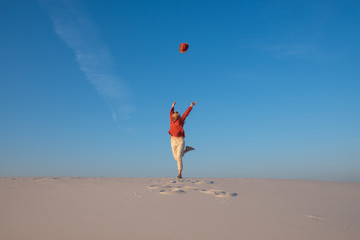 Happy young woman, blonde is jumping and throws her hat