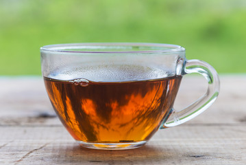 tea concept/transparent cup of black tea outdoors in front of the green grass