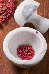 Dry rose pepper in white marble mortar next pestle