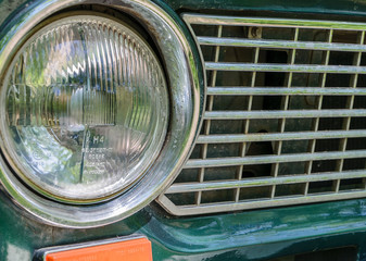 Detail of a rusty green car abandoned by the side of the road