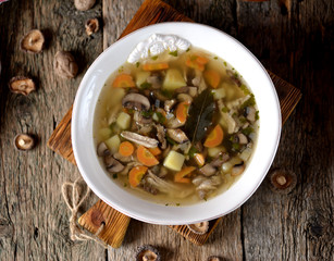 Mushroom soup with potatoes, carrots, onions and chicken meat on an old wooden background. Rustic style.