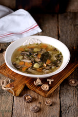 Mushroom soup with potatoes, carrots, onions and chicken meat on an old wooden background. Rustic style.